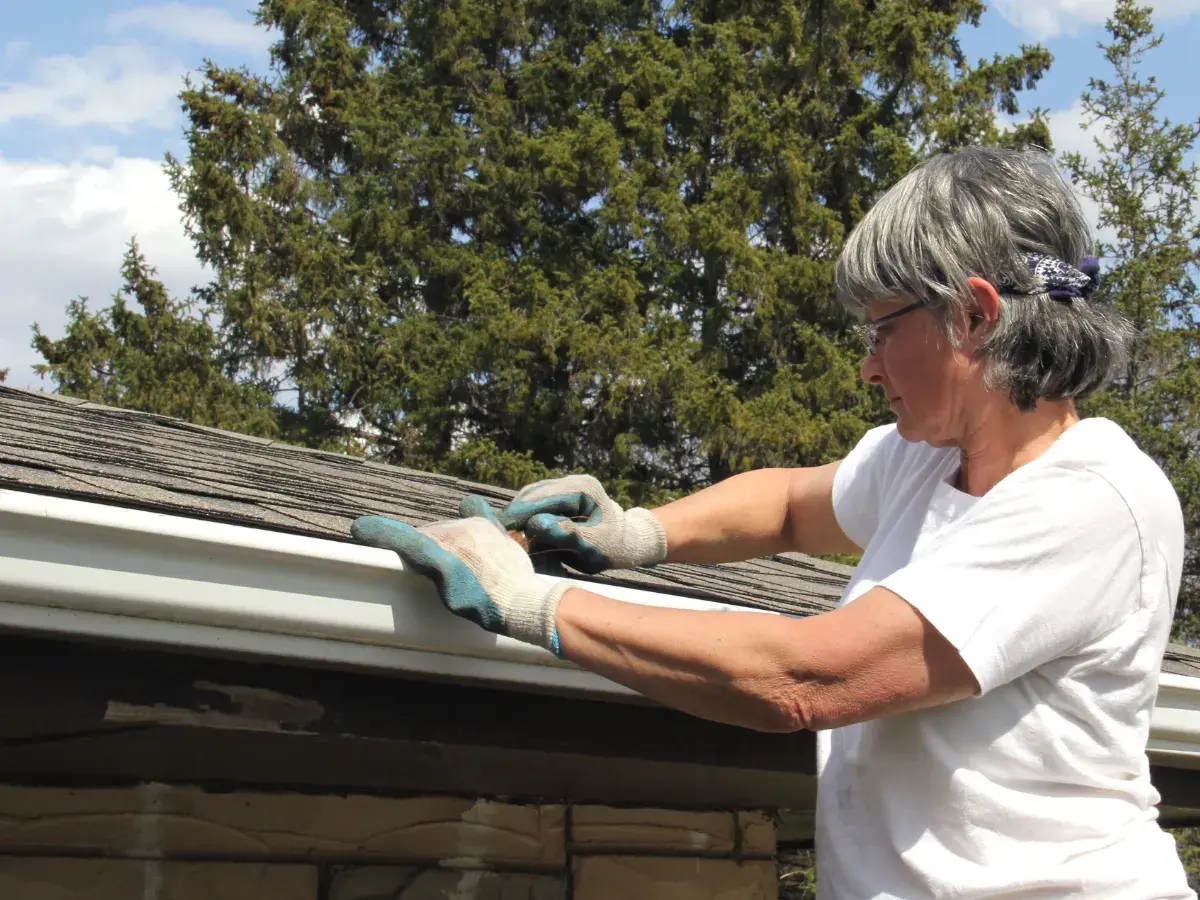 Woman clearing home gutters