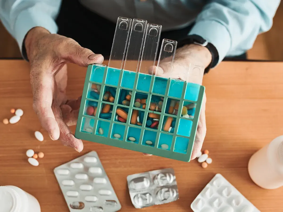 Elderly man filling daily pill planner
